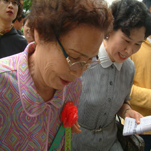꽃을 단 뒤 경로잔치에 들어가시는 할머니