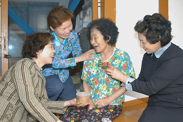 카네이션을 꽂아 드리는 남구여성단체협의회 회원과 기뻐하는 할머니(사진제공. 남구청)