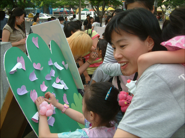 평화나무에 소원달기...'행복한 가족' 이라는 소원을 다는 윤태경(7) 어린이와 김현옥씨..