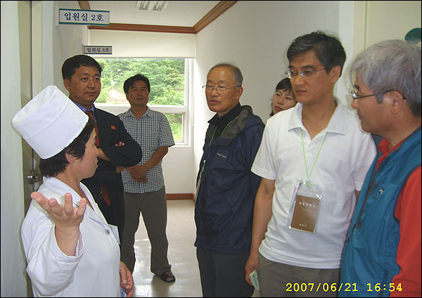 병원 복도에서 설명하고 있는 병원장(여)과 명예병원장(당 간부), 그리고 설명을 듣는 필자 일행.