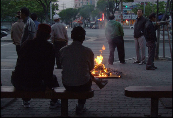 오전 6시쯤의 새벽 인력시장...일거리를 구하지 못한 일용직 노동자들이 모닥불을 쬐며 인력회사 차량을 기다리고 있다(2009.4.15 대구 북비산네거리 인근 / 사진.남승렬 기자)