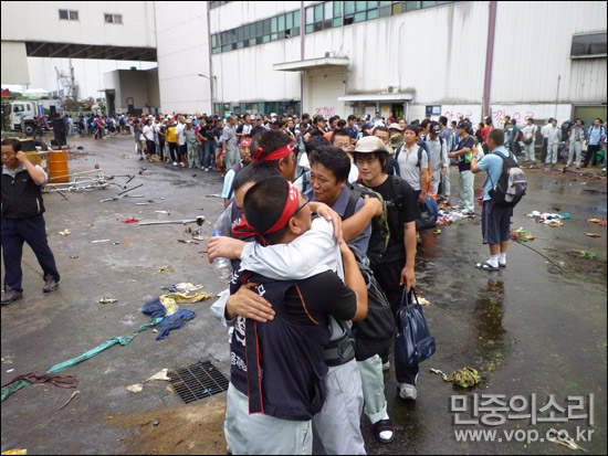 6일 77일간의 농성을 마무리하는 쌍용차 노조 조합원들이 한줄로 서서 한상균 지부장과 포옹하고 있다. 한 지부장은 이날 조인식을 마치고 경찰에 자진 출두했다.ⓒ 민중의소리