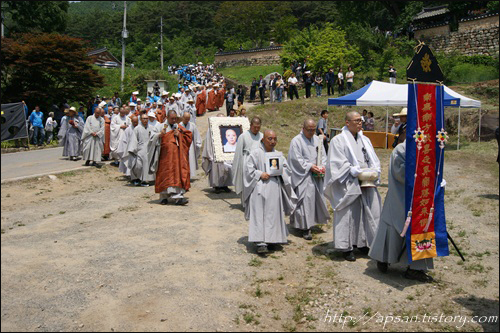 '번'(만장)을 앞세우고 문수스님의 법구가 다비장으로 운구되고 있다. 그 뒤를 대구경북 골재원 노동자들과 추모객들이 따르고 있고, 골재노조에서 준비한 ‘4대강 사업 OUT’라는 플랜카드는 마지막 가시는 스님의 뜻을 다시 한번 기리고 있다 / 사진. 정수근