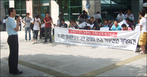 장애인연금 최초 지급일인 7월 30일, 대구지역 장애인들이 국민연금관리공단 대구지사 앞에서 '장애인연금 반납.신청포기선언' 기자회견을 가졌다. 서구의회 장태수(사진 맨 왼쪽) 사회도시위원장은 연대발언을 통해 "이명박 정부가 4대강 사업에 23조원의 돈을 쏟아붓는 동안 장애인들이 받아야 할 지원을 받지 못하고 있다"고 말했다 / 사진. 평화뉴스 박광일 인턴기자