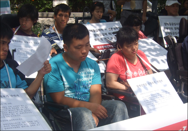 장애인들은 '장애인연금 반납.포기 선언문'을 목에 걸고 제도 개선을 요구했다 / 사진. 평화뉴스 박광일 인턴기자