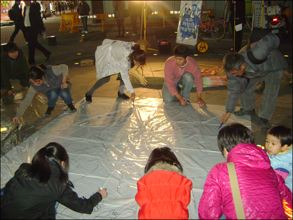 시민들이 중앙파출소 앞 광장 바닥에 펼쳐진 큰 도화지에 강과 자연의 모습을 그리고 있다 / 사진. 평화뉴스 박광일 기자
