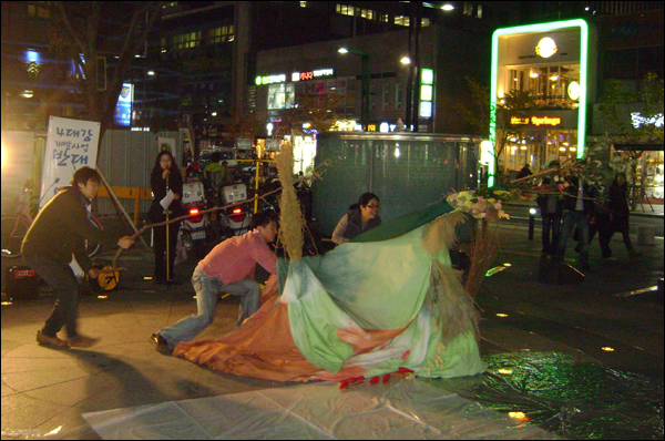 '변사'역을 맡은 권순정(38) 공동대표를 비롯한 연극자리소풍 단원들이 창조신 반고 인형을 들고 시민들 앞으로 다가가고 있다  / 사진. 평화뉴스 박광일 기자