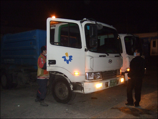 1월 19일 새벽 2시 서구 중리동 차고지에서 노송열(오른쪽) 기사와 환경미화원 정동환씨가 담당구역으로 출발하기 위해 쓰레기수거차량에 오르고 있다 / 사진. 평화뉴스 박광일 기자