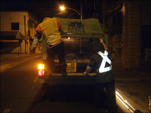 쓰레기를 다 싣고난 뒤 얼른 수거차량에 오르는 환경미화원들 / 사진. 평화뉴스 박광일 기자