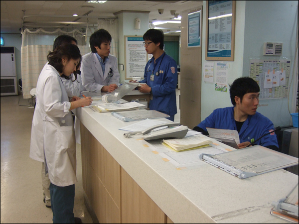 응급의학 서적을 펼쳐놓고 인턴 의사들과 스터디하는 전공의 서익권씨(왼쪽 두 번째)와 진료기록차트를 살펴보고 있는 수련의 1년차 김태권씨(왼쪽 첫 번째) / 사진. 평화뉴스 박광일 기자