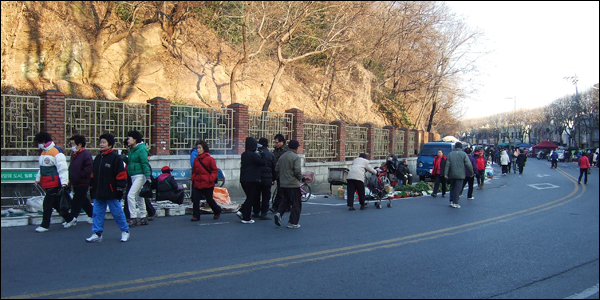 달성공원 담벼락을 따라 길게 늘어선 반짝시장과 이곳을 찾은 사람들의 모습. 운동을 하러나온 사람들과 물건을 사러온 손님들로 뒤섞여있다 / 사진. 평화뉴스 박광일 기자