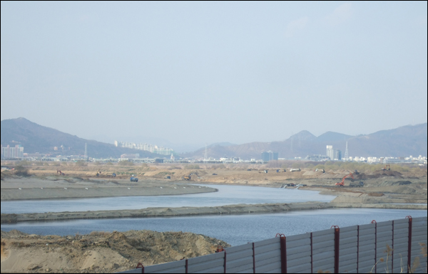 화원유원지 강변주차장에서 바라본 4대강 공사 현장의 풍경. 곳곳에 누런 흙더미가 쌓여있고, 포크레인들이 강 주변을 파헤치고 있어 황량한 모습을 보이고 있다 / 사진. 평화뉴스 박광일 기자