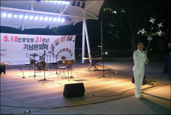 민족예술인 이상옥 씨가 바람개비 5개가 매달린 나뭇가지를 이용한 마임 공연을 선보이고 있다. 이상옥씨는 공연 전 관객들에게 18개의 바람개비를 나눠주며 "자신이 들고 있는 바람개비 5개와 관객들이 들고있는 바람개비 18개가 '5.18'을 의미한다"고 말했다 / 사진. 평화뉴스 박광일 기자