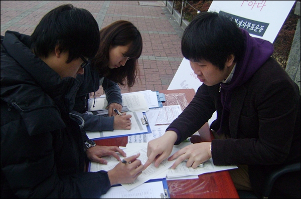 대구참여연대 이승호 간사가 부재자 신고를 하고 있는 학생을 돕고 있다(2012.3.19 경북대 도서관 앞) / 사진.평화뉴스 김영화 수습기자