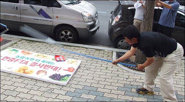 "한중 FTA 협상 중단"을 촉구하며 도리깨로 피켓을 내리치는 최상은 전국농민경북도연맹 의장(2012.6.29.새누리당 대구경북 시.도당 앞) / 사진. 평화뉴스 김영화 기자
