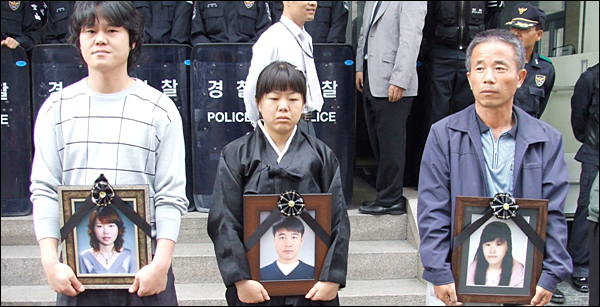 삼성반도체 기흥공장에서 일하다 '급수골수성백혈병' 판정을 받고 목숨을 잃은 고 이숙영, 황민웅, 황유미씨. 유가족들이 "산업재해 인정"을 촉구하며 근로복지공단 앞에서 영정사진을 든 모습 / 사진 제공. 이종란 노무사