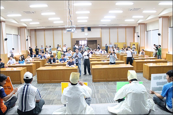 농민들이 설명회장 단성에 앉아 농식품부 관계자들에게 "설명회 중단"을 요구하고 있다(2014.6.24) / 사진.평화뉴스 김영화 기자