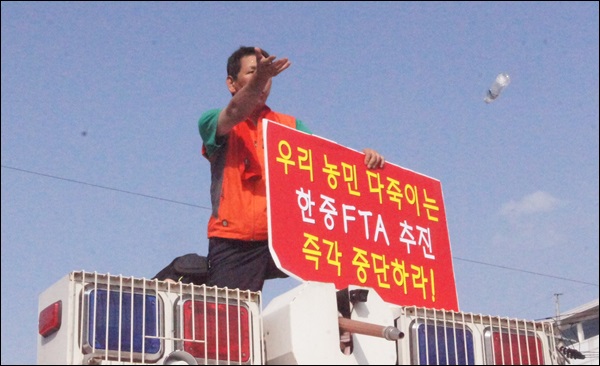 "우리 농민 다죽이는 한중FTA " 피켓을 든 농민이 경찰 살수차량 위에 올라타 항의하는 모습(2014.7.14.대구 북구 산격동 엑스코) / 사진.평화뉴스 김영화 기자