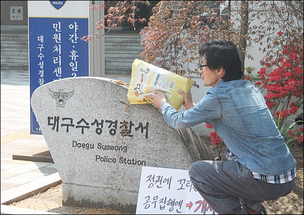 대구수성경찰서 앞에서 개사료를 뿌리는 박씨(2015.4.21) / 사진.평화뉴스 김영화 기자