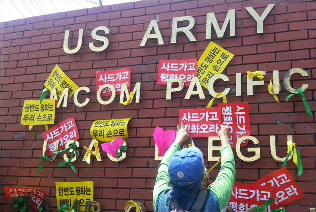 캠프캐럴 정문 벽에 걸린 평화리본과 피켓(2016.7.18) / 사진.평화뉴스 김지연 기자