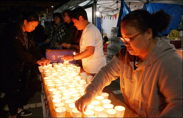 집회 시작 전 주민들에게 촛불을 나눠주는 자원봉사자들(2016.10.20) / 사진.평화뉴스 김지연 기자