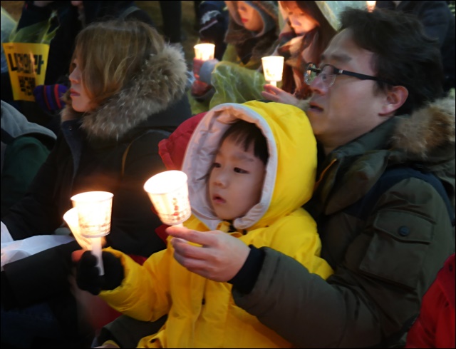 아버지 품에 안겨 촛불을 치켜 든 아이(2016.11.26) / 사진.평화뉴스 김지연 기자