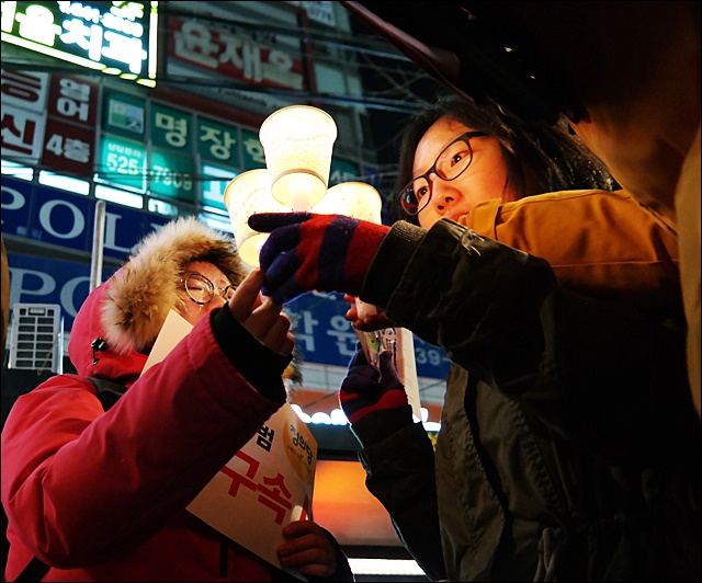 윤재옥 새누리 의원 지역사무소 앞에서 촛불을 나누고 있는 달서 주민들(2016.12.7) / 사진.평화뉴스 김지연 기자