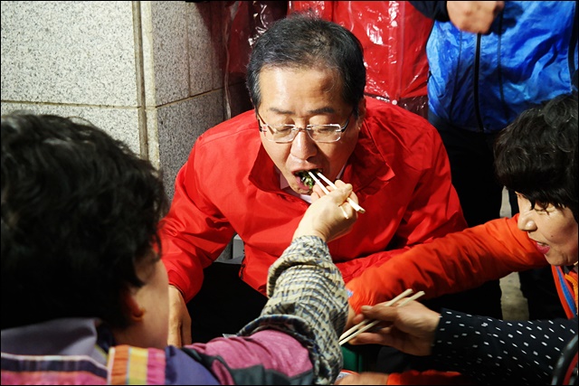 칠성시장 상인이 주는 부추전을 먹고 있는 홍 후보(2017.4.17) / 사진.평화뉴스 김지연 기자