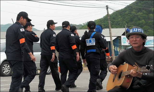 사드반대 주민 뒤로 경찰들이 걸어가고 있다(2017.4.25) / 사진.평화뉴스 김지연 기자