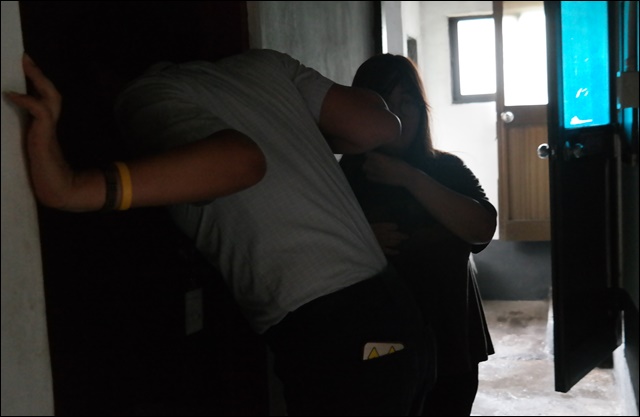 어두운 방 안의 거주인에게 쉼터 직원이 안부를 묻고 있다(2018.7.27) / 사진. 평화뉴스 김지연 기자