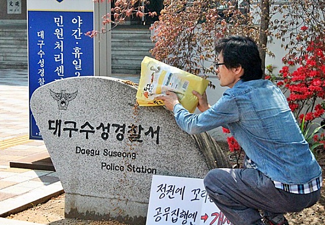 박씨가 전단지 수사에 항의해 수성경찰서 비석에 개사료를 뿌렸다(2015.4.21) / 사진.평화뉴스 김영화 기자