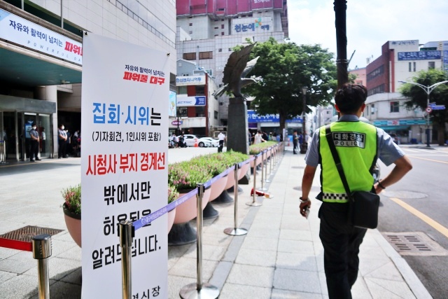 "집회와 시위는 시청사 부지 경계선 밖에서만 허용됩니다."...대구시 중구 동인동 대구시청 동인청사 앞 입간판 앞에서 1인 시위를 하는 대구시민 앞으로 대화경찰이 지나가고 있다.(2022.7.21) / 사진.평화뉴스 김영화 기자