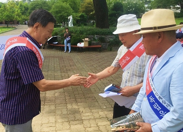 대한광복회 독립지사 후손인 우대현 대표와 김길조 선생에게 <대구 독립운동유적 100곳 답사여행> 책을 봉정하는 김상태 독립운동정신계승사업회 고문(2018.8.25.달성공원) / 사진.평화뉴스 김영화 기자