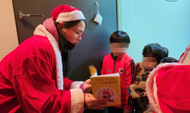 산타가 3형제에게 책 마술을 보여주고 있다.(2023.12.22) / 사진.평화뉴스 정준민 기자
