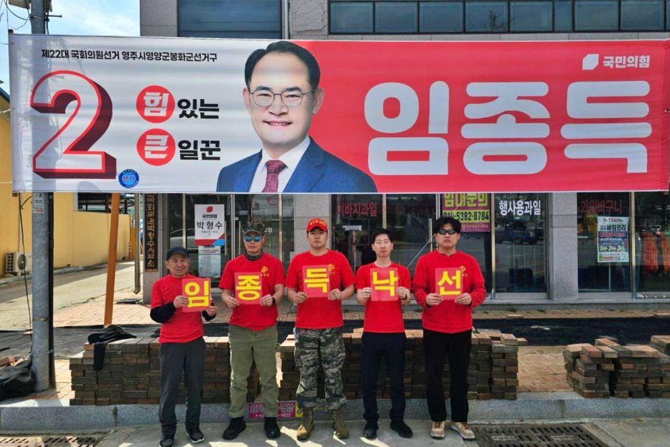 붉은색 티셔츠를 입은 해병대 예비역들이 경북 영주 국민의힘 임 후보 선거 현수막 아래에서 "임종득 낙선" 피켓팅을 벌이고 있다.(2024.3.30) / 사진 출처.해병대 예비역 김규현 페이스북 