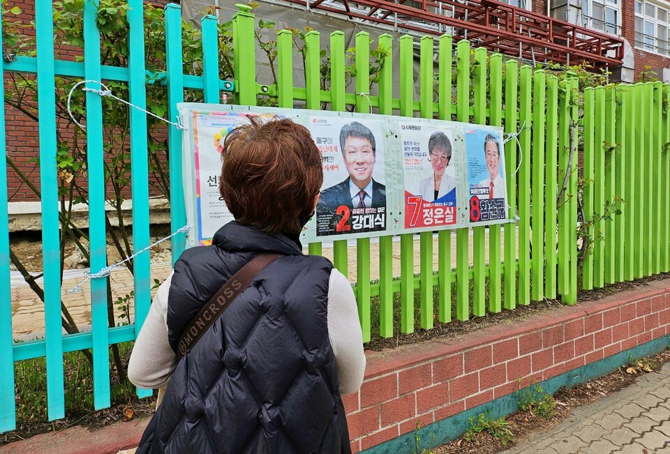 한 유권자가 동구 율하초등학교 앞에 걸린 선거 공보물을 지켜보고 있다.(2024.4.4) / 사진.평화뉴스 정준민 기자