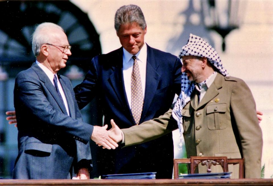 1993년 9월 13일 워싱턴 백악관에서 이스라엘-PLO(팔레스타인 해방기구) 평화 협정에 서명한 후 빌클린턴 미국 대통령이 그 사이에 서 있는 가운데 야세르 아라파트 PLO 의장(오른쪽)이 이츠하크 라빈 이스라엘 총리(왼쪽)와 악수하고 있다. / 사진. Gary Hershorn, Reuters