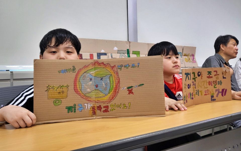 "지구가 불타고 있어요. 기후위기를 막아요, 지구야 조금만 참아줘. 도와줄게" 기후위기를 알리는 그림과 문구를 적은 피켓을 들고 대구환경청 '환경의날 기념식'에 참석한 화동초 학생들(2024.6.5) / 사진.평화뉴스 김영화 기자