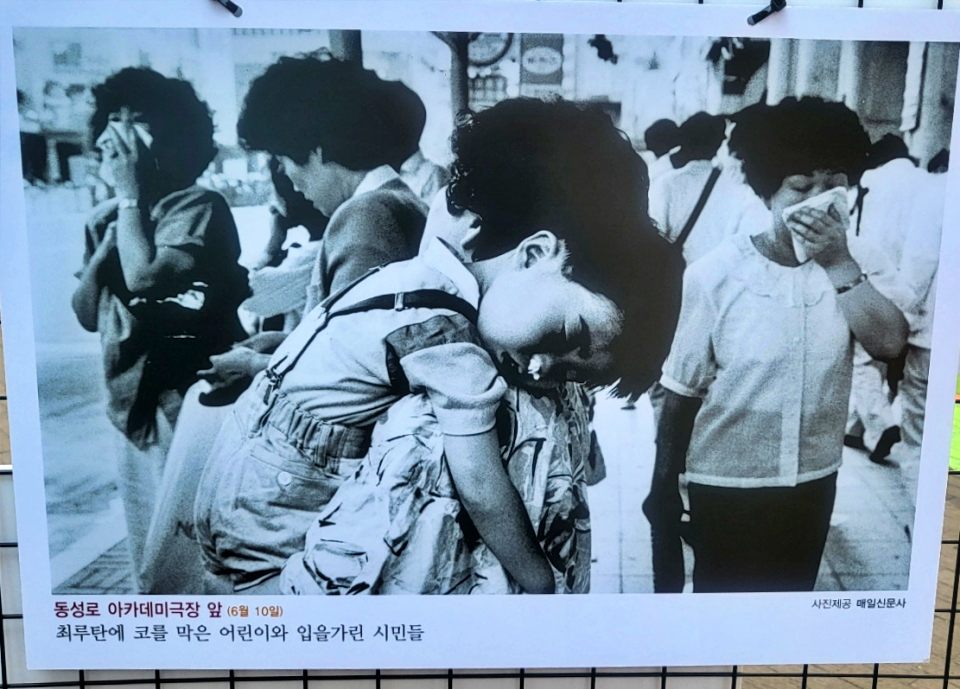1987년 6월 10일 대구 동성로 아카데미극장 앞에서 최루탄에 코를 막은 어린이와 입을 가린 시민들(2024.6.10 '1987년 대구의 6월 항쟁 사진전'. 대구 동성로 민주광장 - 사진 제공. 매일신문사) / 사진.평화뉴스 김영화 기자