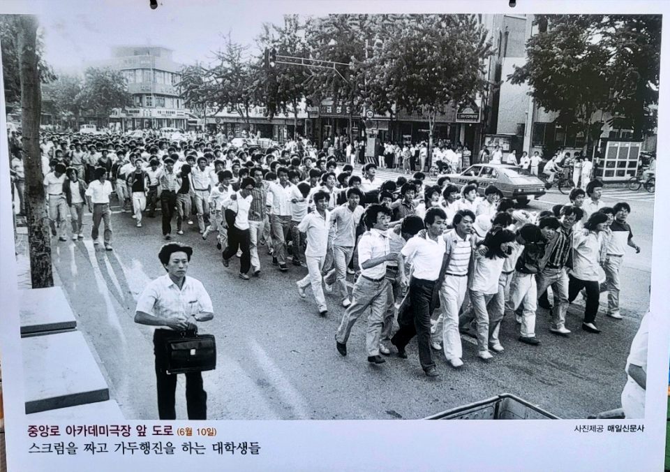 1987년 6월 10일 대구 중앙로 아카데미극장 앞 도로에서 스크럼을 짜고 가두행진을 하는 대학생들(2024.6.10 '1987년 대구의 6월 항쟁 사진전'. 대구 동성로 민주광장 - 사진 제공. 매일신문사) / 사진.평화뉴스 김영화 기자