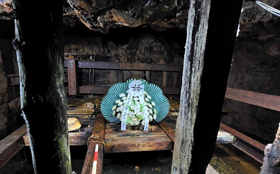 수평2굴 어두컴컴한 갱도 끝에 도달하면 유해를 꺼냈던 깊이 40여m의 수직갱도가 보인다. 지금은 물이 가득차 우물처럼 변했다. 그 위로 정근식 전 진실화해위원회 위원장의 조화가 놓여져 있다.(2024.6.18)/ 사진.평화뉴스 김영화 기자