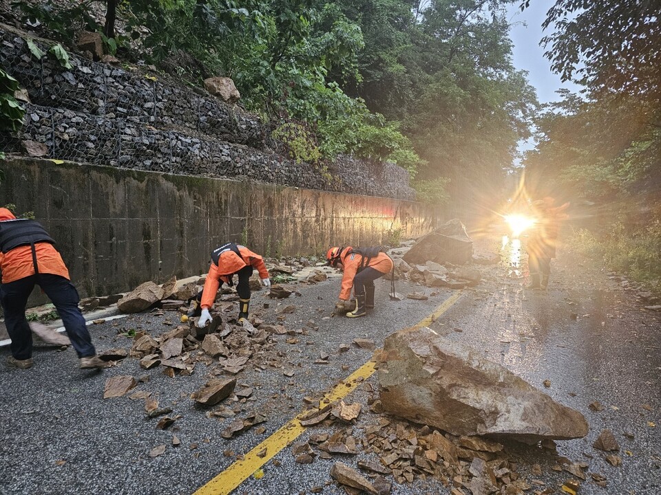 폭우로 인해 산에 있던 바위와 돌들이 경북 안동시 예안면 도로 위로 쏟아져 소방대원들이 치우고 있다.(2024.7.8) / 사진.경복소방본부