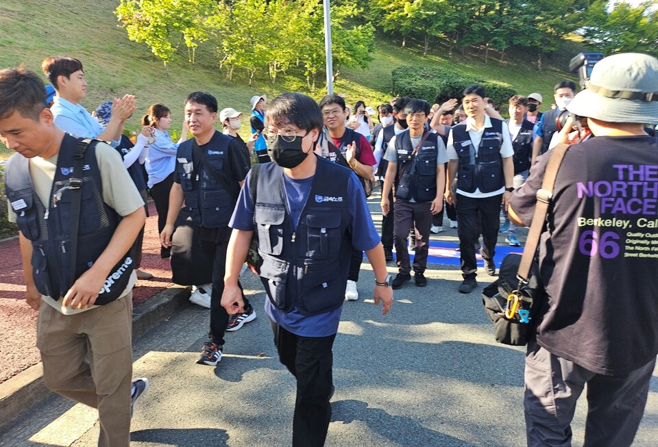 아사히글라스 노동자들이 "2015년 6월 30일"이라고 적힌 현수막을 밟고 지나가고 있다.(2024.8.1) / 사진.평화뉴스 정준민 기자