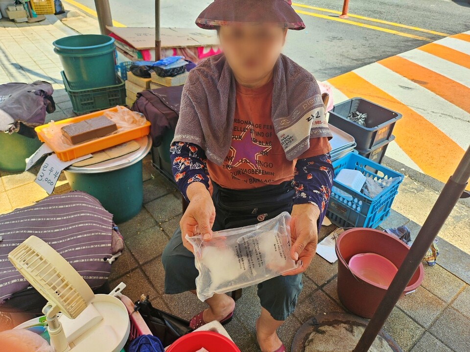 이모(68) 할머니가 얼린 수건을 목에 두르고, 얼음주머니를 들고 있다.(2024.8.2.동구시장) / 사진. 평화뉴스 정준민 기자