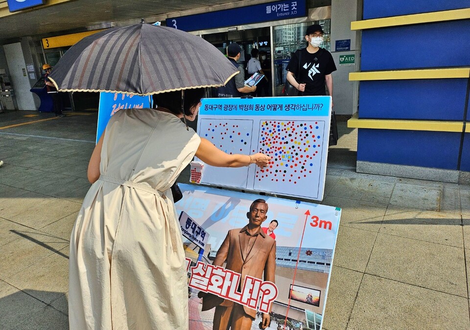한 시민이 동대구역 광장에 박정희 동상을 설치하는 것에 대한 의견을 묻는 판넬에 "반대" 스티커를 붙이고 있다(2024.9.13) / 사진.평화뉴스 정준민 기자