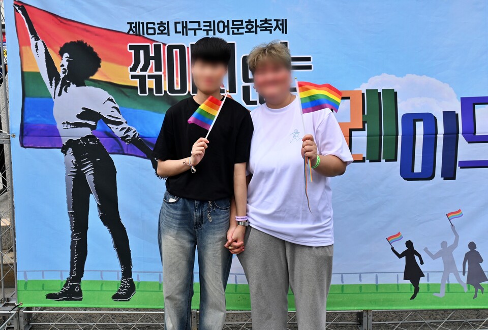 한 레즈비언 커플이 대구퀴어문화축제 행사장에 마련된 포토존에서 손을 잡고 무지개 깃발을 흔들고 있다.(2024.9.28) / 사진.평화뉴스 정준민 기자