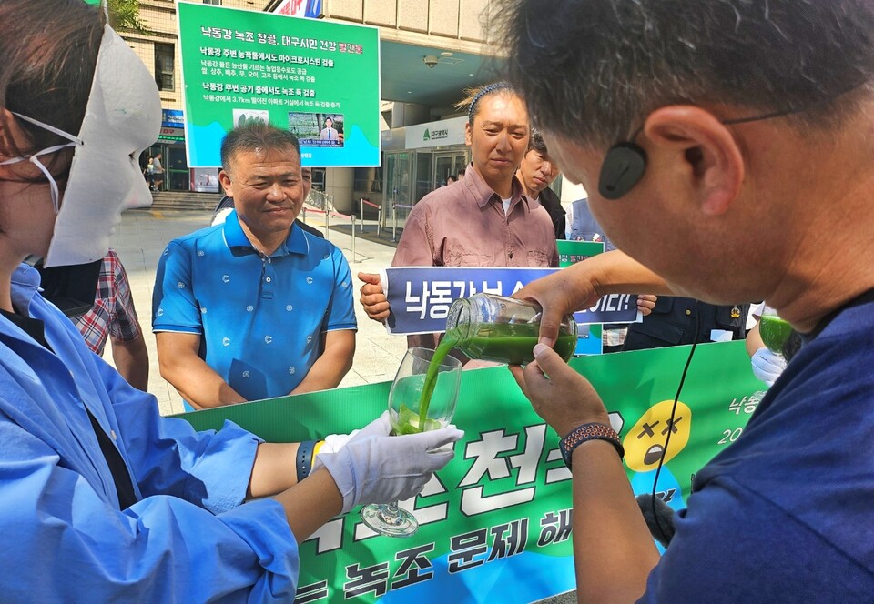 정수근 대구환경운동연합 사무처장이 강정고령보에서 채취한 녹조 강물을 컵에 붓고 있다.(2024.9.30) / 사진.평화뉴스 정준민 기자