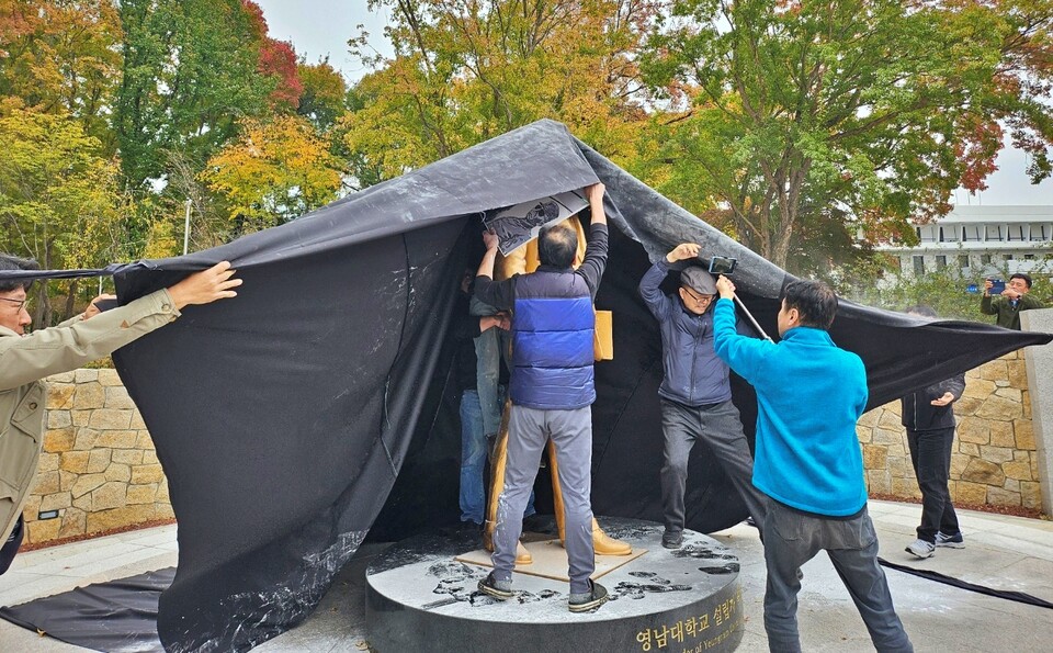 영남대 민주동문회 회원들이 박정희 동상에 검은 천을 씌우고 있다.(2024.11.10) / 사진.평화뉴스 정준민 기자