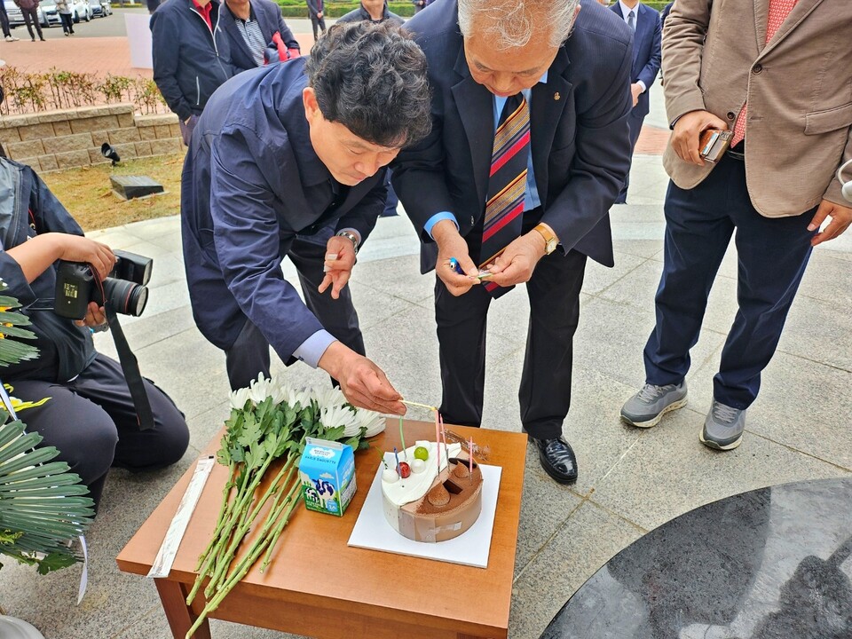영남대 총동창회 회원들이 박정희 동상 옆에 놓인 생일 케이크에 초를 붙이고 있다.(2024.11.14) / 사진.평화뉴스 정준민 기자