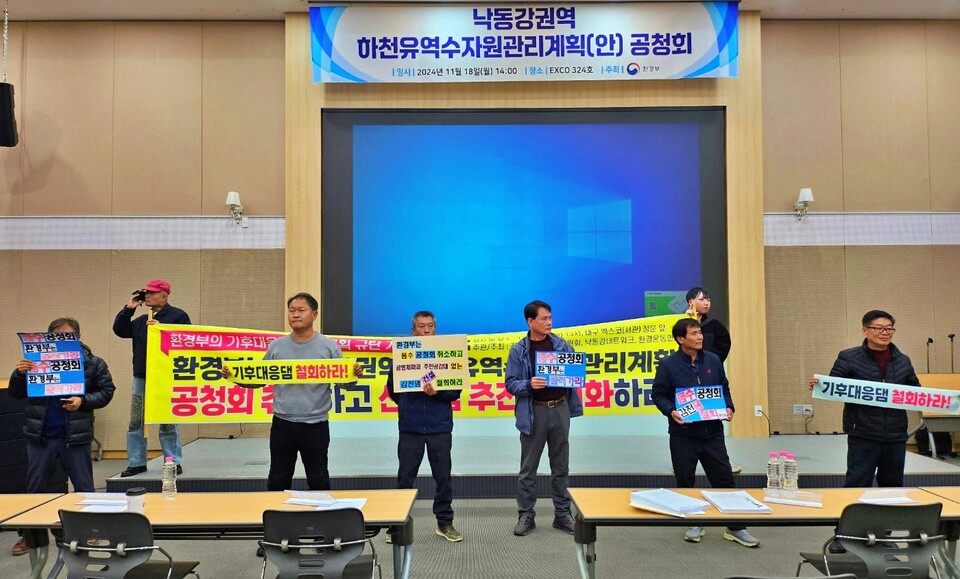 경북 김천 대덕면 감천댐 후보지 주민들과 환경단체 인사들이 환경부 '하천유역수자원관리계획 공청회' 시작과 함께 단상 앞에 서서 피켓팅을 벌이고 있다.(2024.11.18) / 사진.평화뉴스 정준민 기자